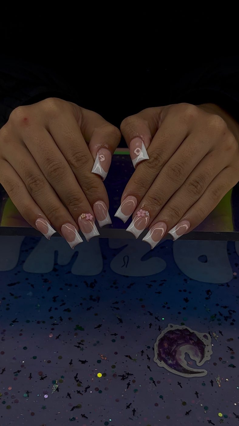 Lia nail art with soft pink French tips, white details, and small accent designs.