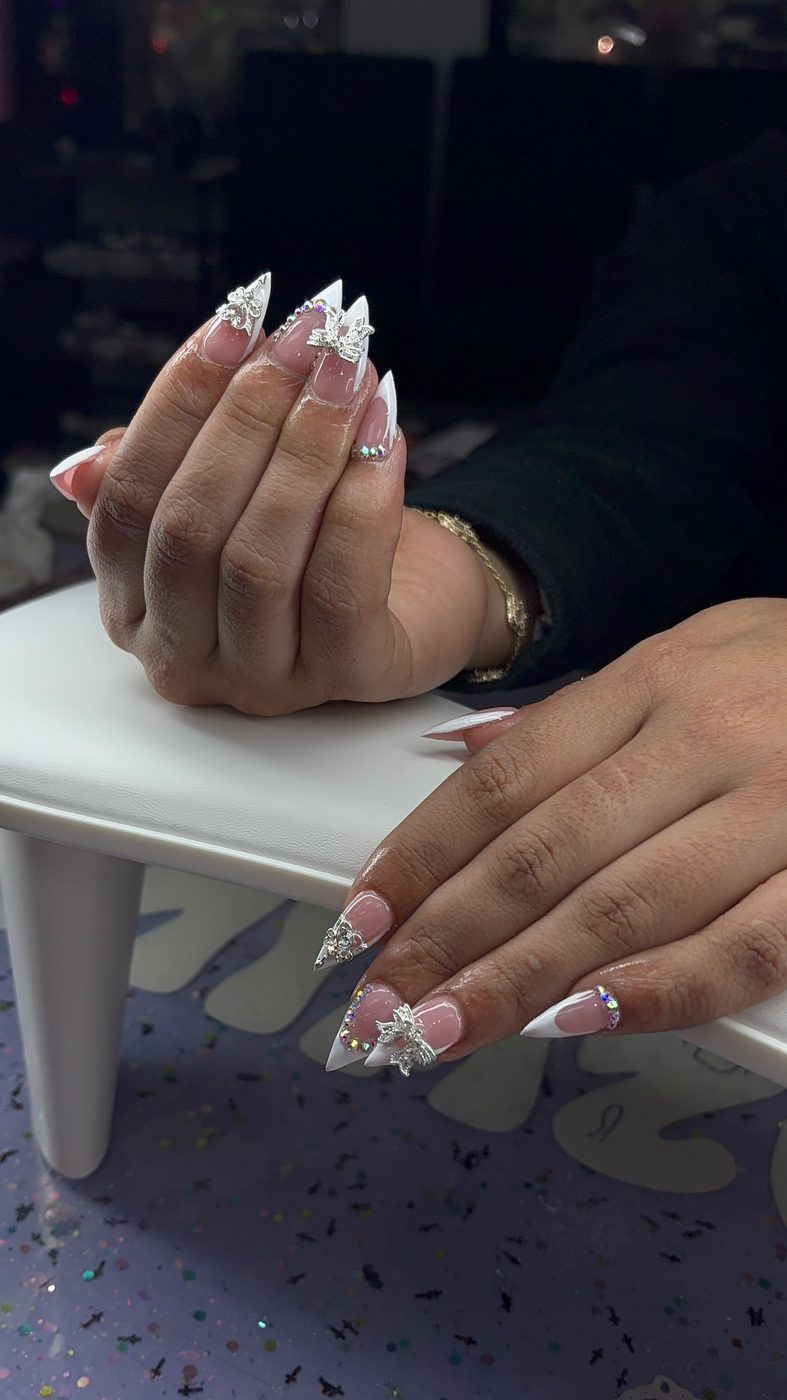 Lia nail art with white sculpted tips, glitter, and 3D bow details.