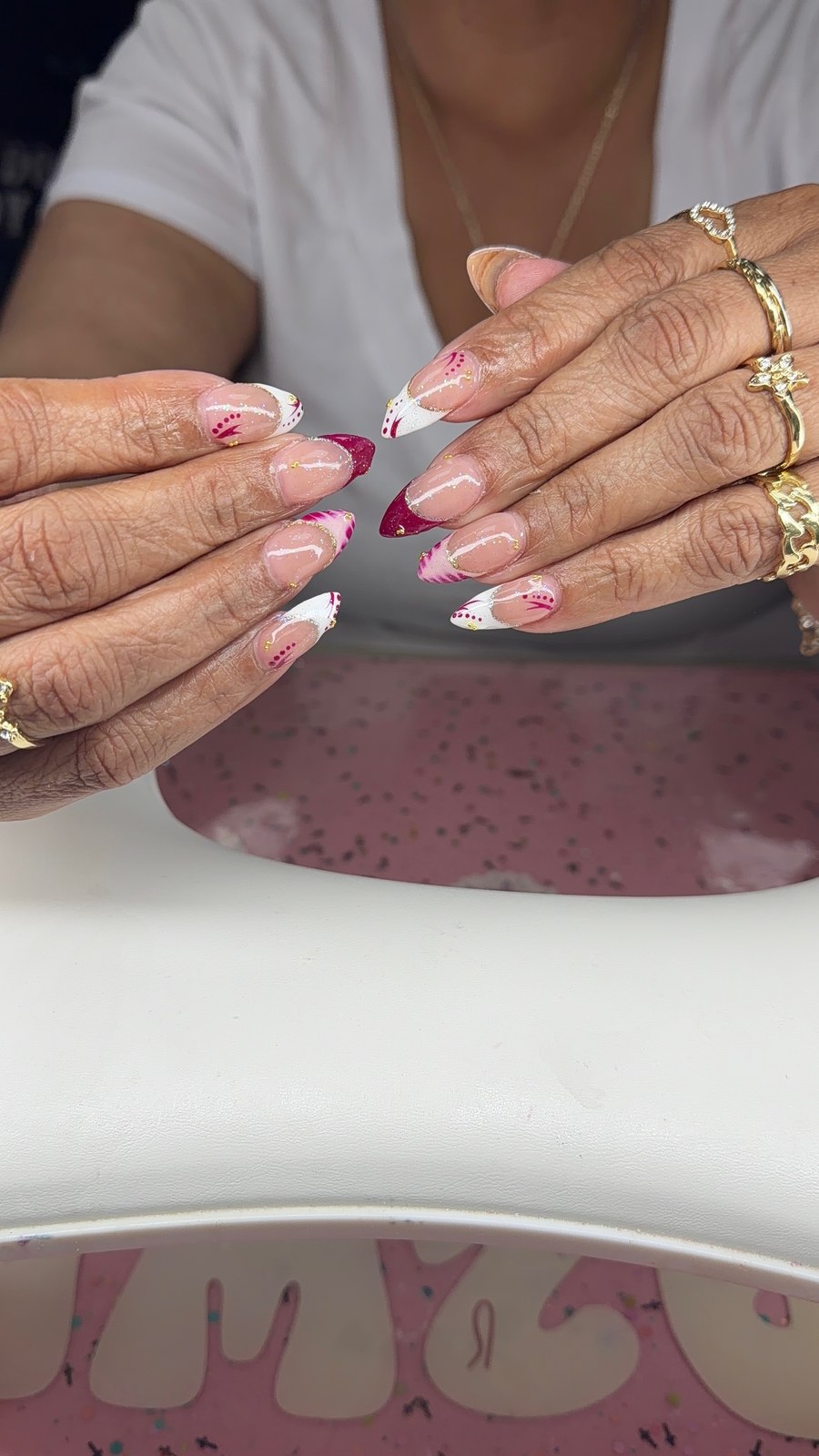 Serenity nail art with burgundy French tips, glitter, and gold accents.