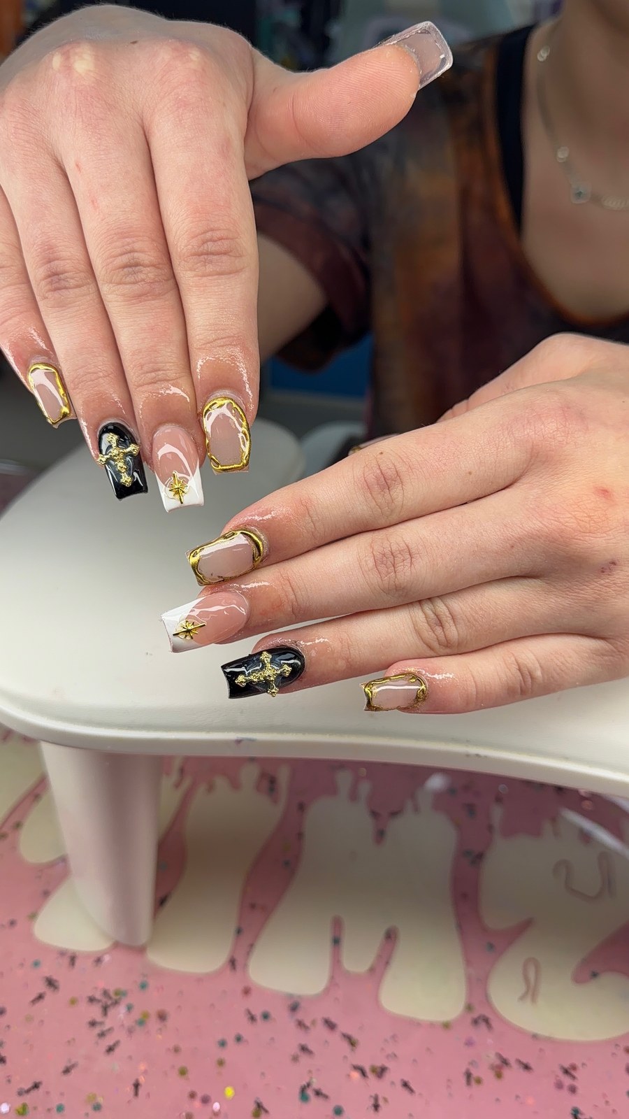 Serenity nail art with black and nude nails, gold chrome frames, and star charms.