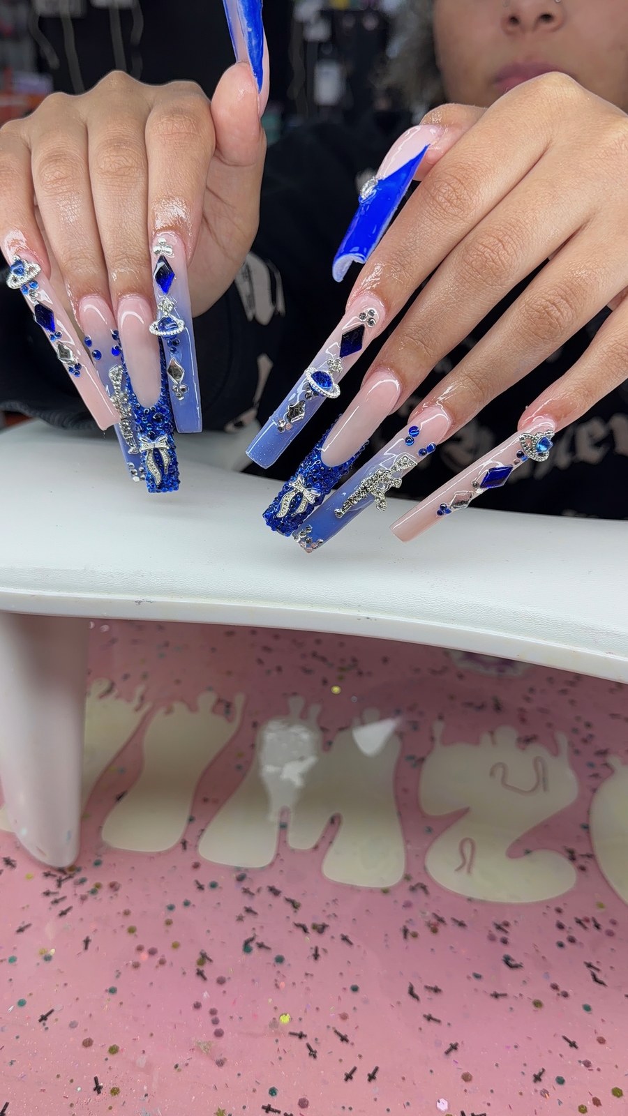 Serenity nail art with royal blue charms, rhinestones, and long sculpted tips.